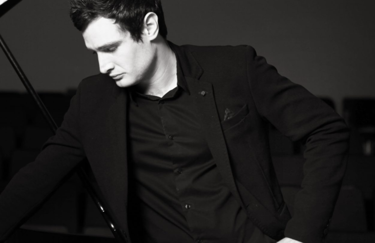 A man posing by the piano.