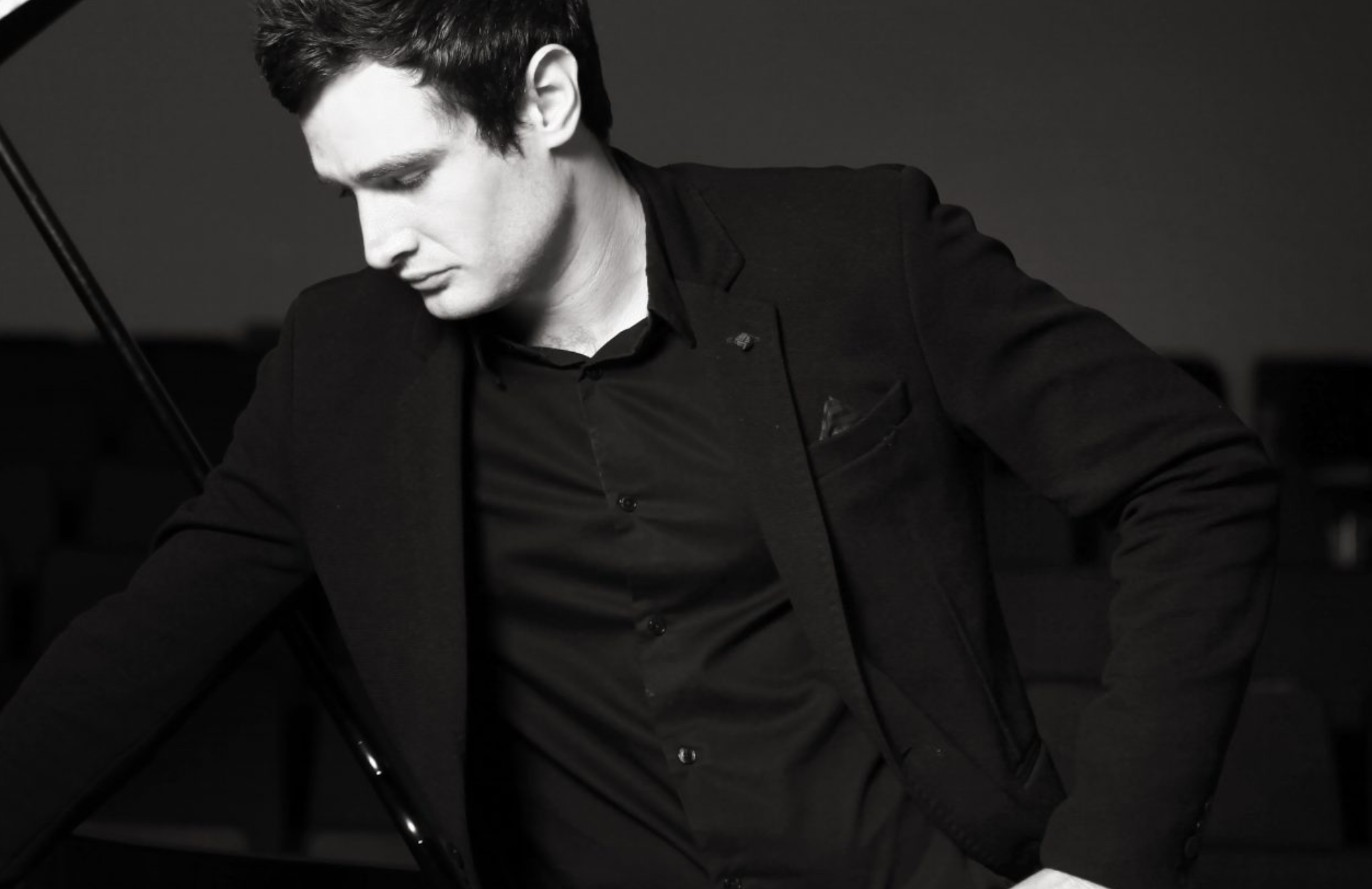 A man posing by the piano.